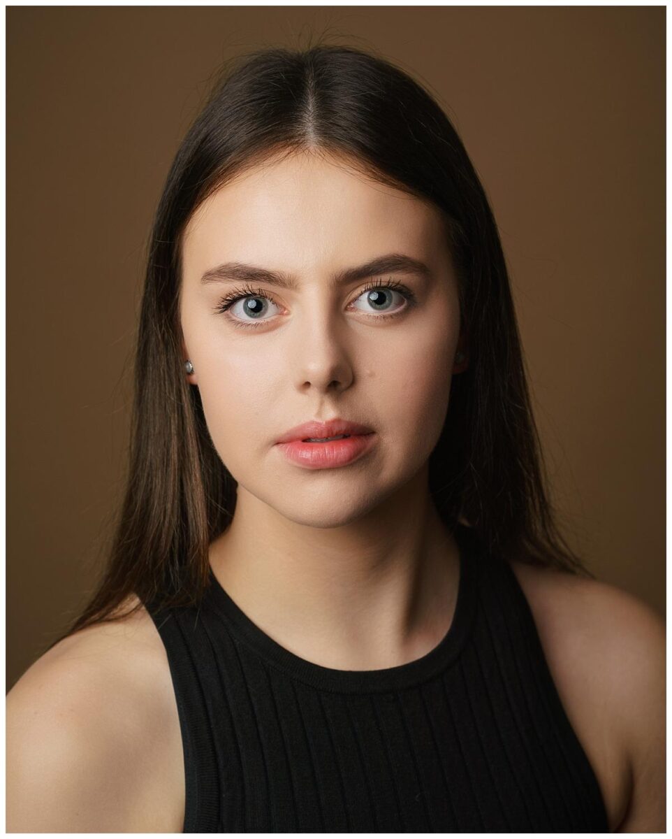 Professional headshot photograph taken by Northern Ireland's top headshot photographer in Belfast of a girl straight on to camera wearing a black top on a brown backdrop