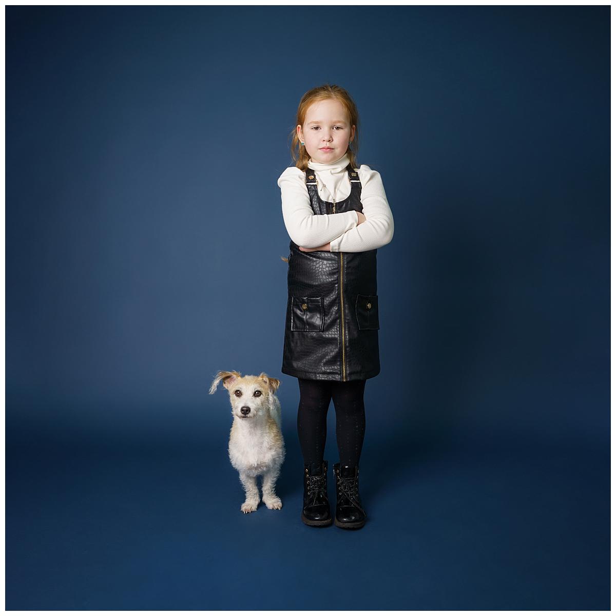 Professional pet photograph, taken by Northern Ireland's top pet photographer in Belfast of small dog with a little girl on a navy backdrop