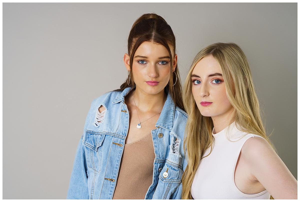 Professional Family photograph taken by one of Northern Ireland's top Family photographers in Belfast of two teenage girls posing on a light grey backdrop