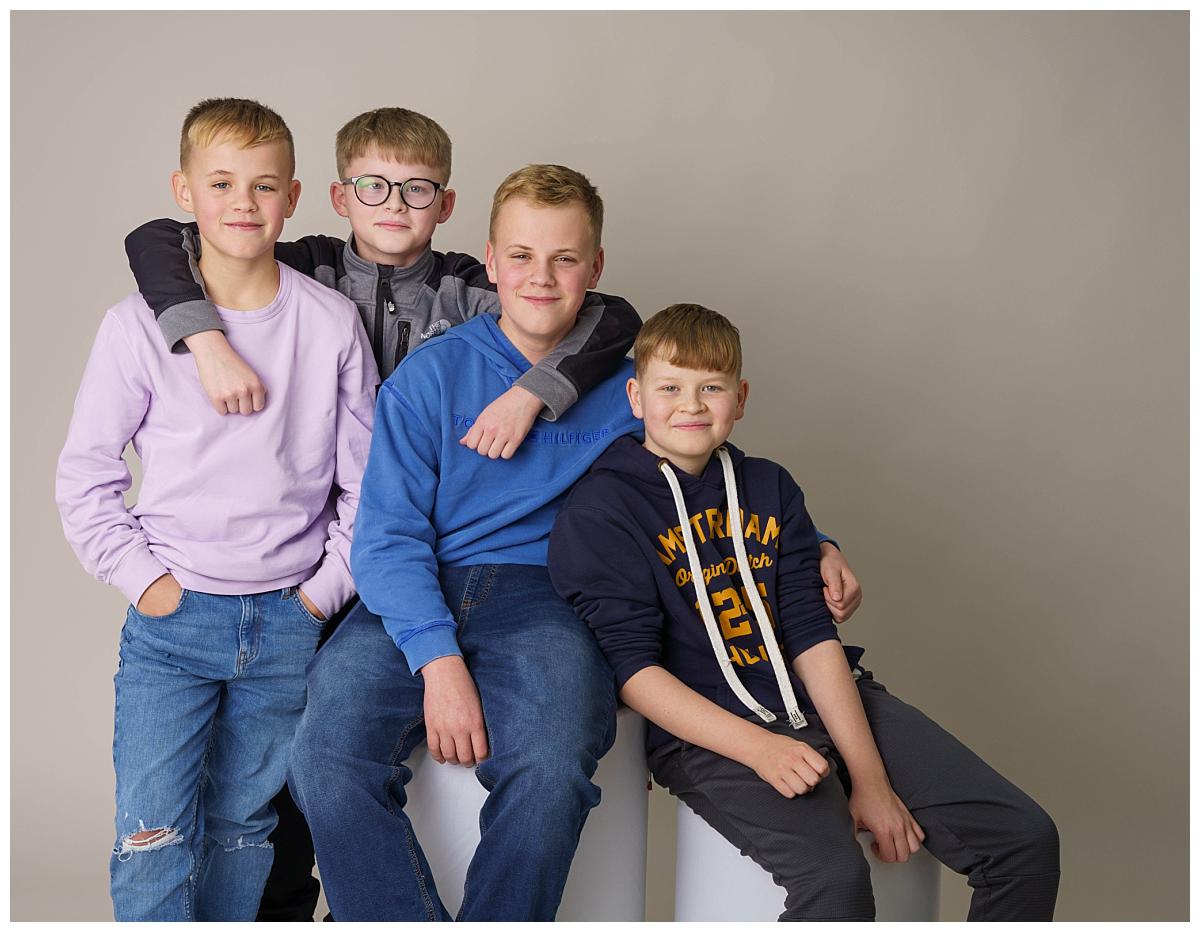 Professional Family photograph taken by one of Northern Ireland's top Family photographers in Belfast of four teenage lads sat on a light grey backdrop
