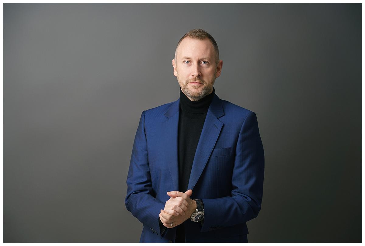 Professional headshot photograph taken by Northern Ireland's top headshot photographer in Belfast of a man in a blue suit on a grey backdrop