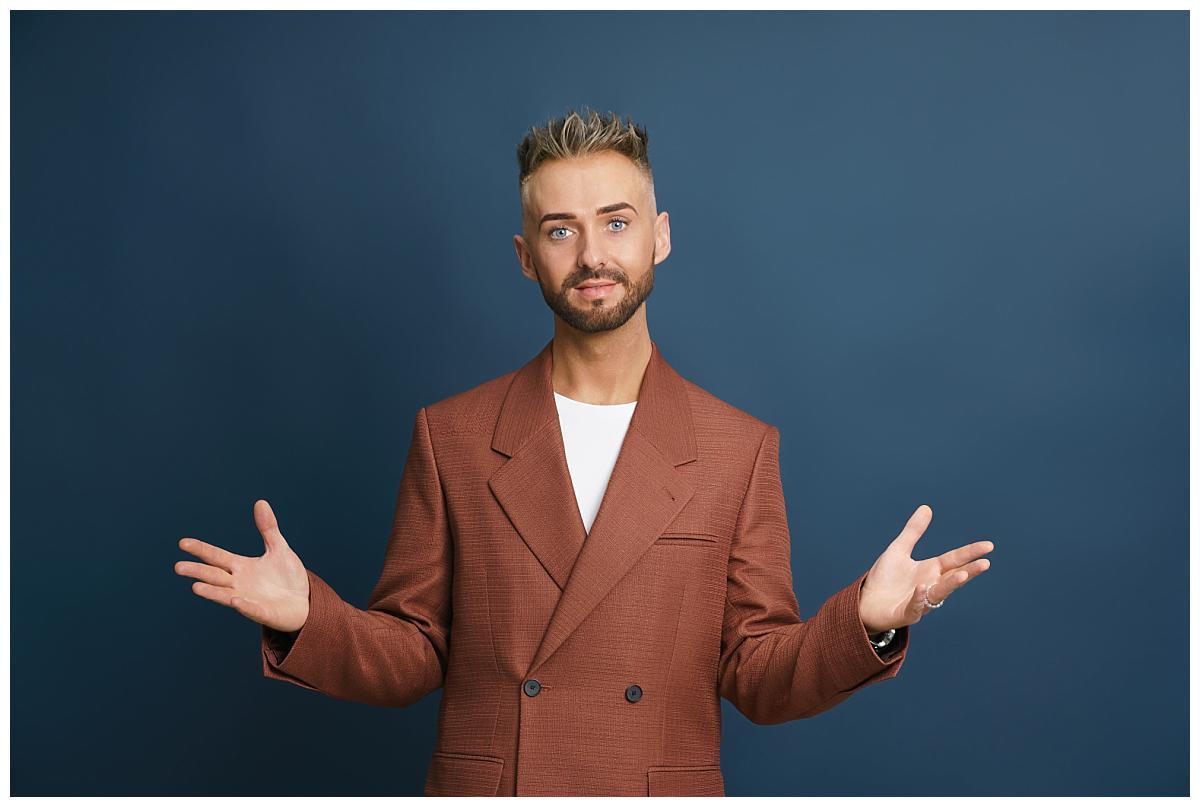 Professional headshot photograph taken by Northern Ireland's top headshot photographer in Belfast of a man in a suit in on navy background hands up